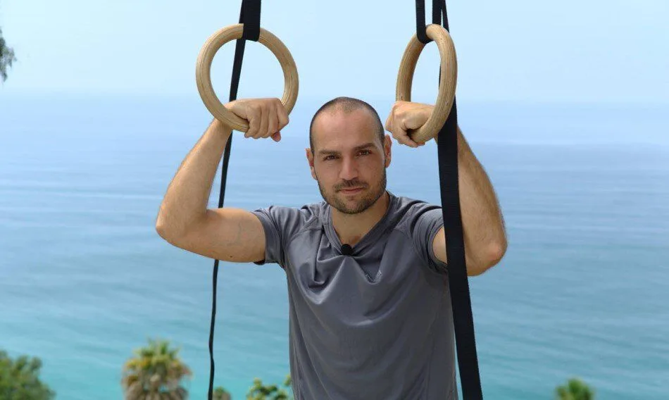 Athlete demonstrating gymnastic rings exercises outdoors, highlighting strength and stability training