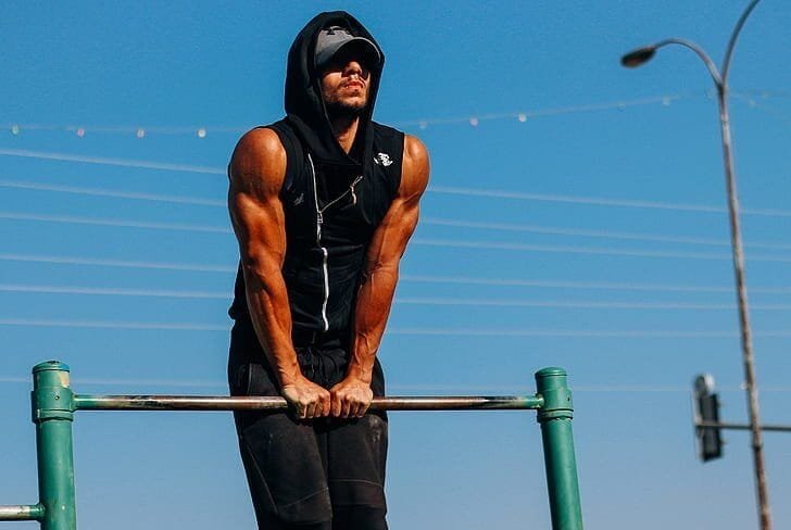 Man showing muscular arms while performing straight bar dips