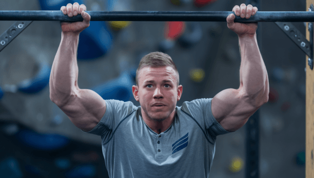 Athlete performing pull-ups, demonstrating muscular upper body strength and progressive overload in calisthenics training